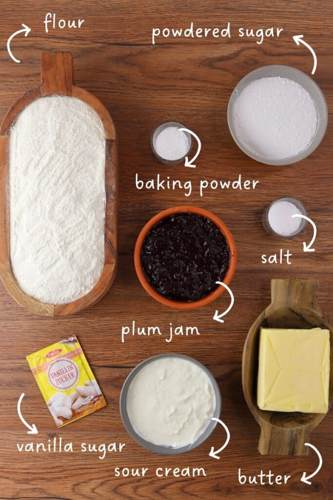 gathering ingredients for empanada cookies: flour, butter, sour cream, salt, baking powder, powdered sugar, vanilla suga and plum jam